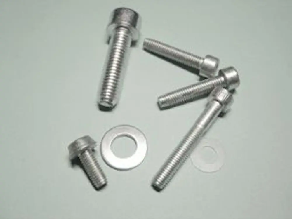 Schrauben und Unterlegscheiben aus Metall, möglicherweise von der Marke Remeha, auf einer hellen Oberfläche angeordnet.